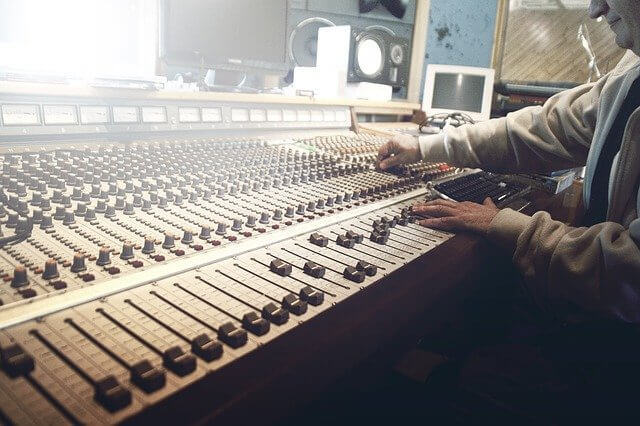 Una persona usando un mezclador de sonido en un estudio de grabación