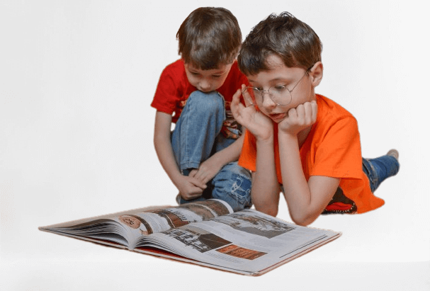 Dos niños leyendo un libro en el suelo