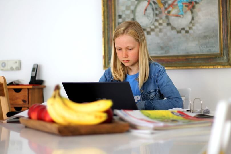 Una niña que recibe educación en casa lee un libro en una mesa